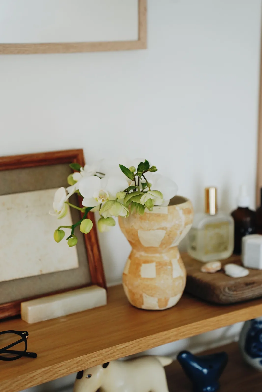 花を生けた器と額のある棚