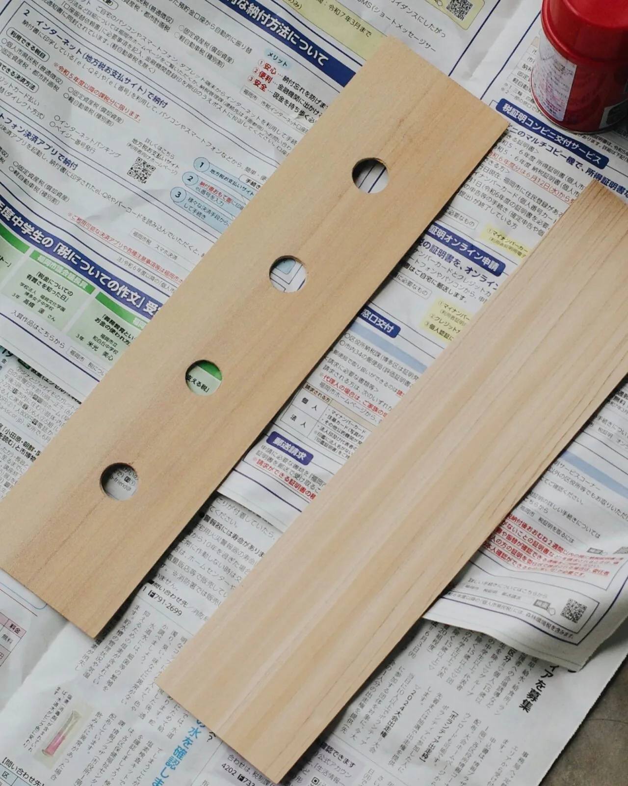 新聞紙の上で穴を開けた木の板2枚